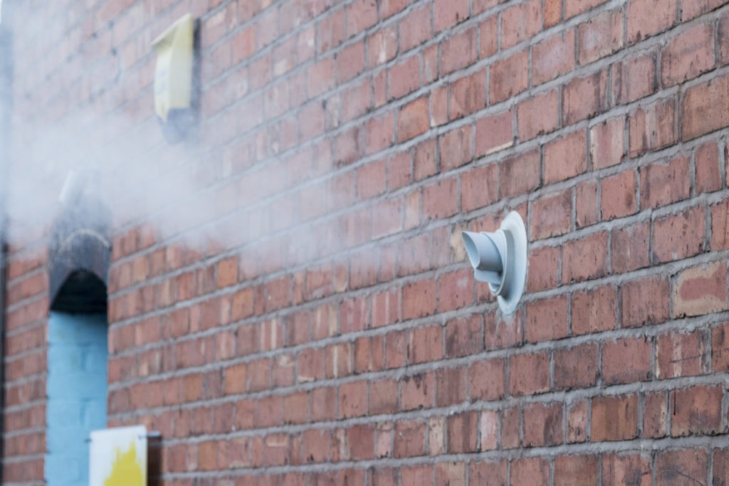Steam vent from a gas boiler on a brick wall